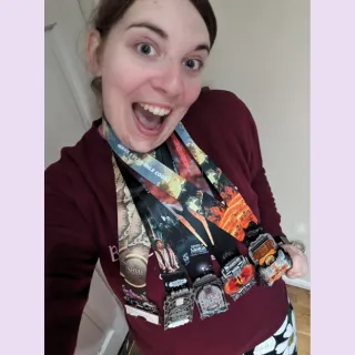 Rachel looks into the camera with an excited expression on her face, she is wearing five Lord of the Rings Conqueror Challenge medals