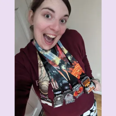 Rachel looks into the camera with an excited expression on her face, she is wearing five Lord of the Rings Conqueror Challenge medals